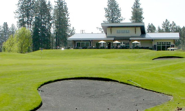 Sand trap on golf course in foreground, club house in distant background.