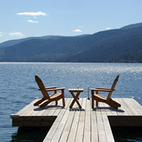 Two lounge chairs await on a dock extending over Christina Lake, B.C.