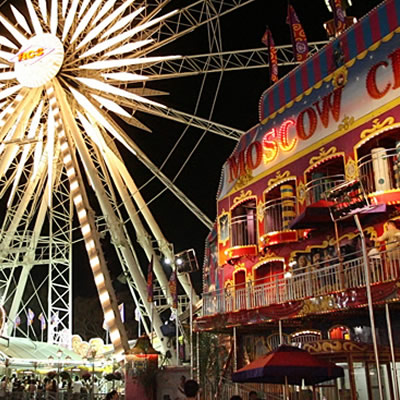 Carnival with ferris wheel, lit up at night. 