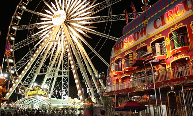 Carnival with ferris wheel, lit up at night. 
