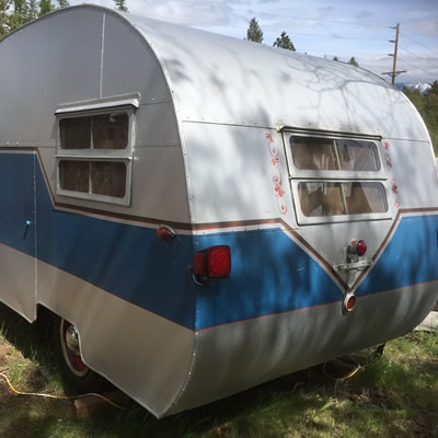 A blue and white Cozy Cruiser trailer, view from the rear. 