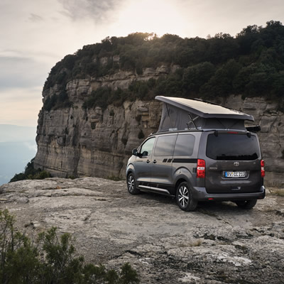 Crosscamp camper van parked on edge of cliff overlooking valley. 