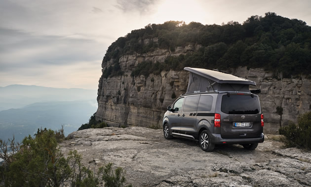 Crosscamp camper van parked on edge of cliff overlooking valley. 