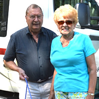 Senior couple and large dog, beside their motorhome