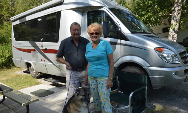 Senior couple and large dog, beside their motorhome
