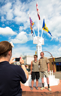 A couple takes a picture at the Mile 0 post of the Alaska Highway in Dawson Creek.