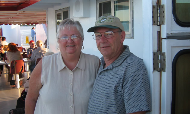 Senior couple stand outside their RV.