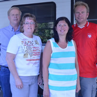 Two couples in summer clothing stand beside a motorhome