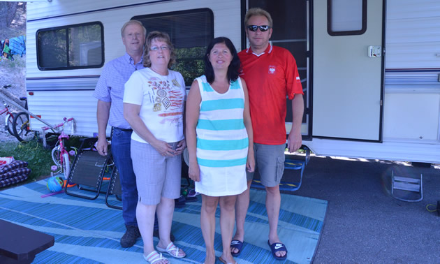 Two couples in summer clothing stand beside a motorhome