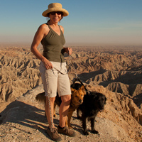 Woman and two dogs on a high ridge overlooking barren badlands