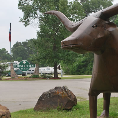 Picture of bull statue with Forest Retreat RV Park sign in background. 