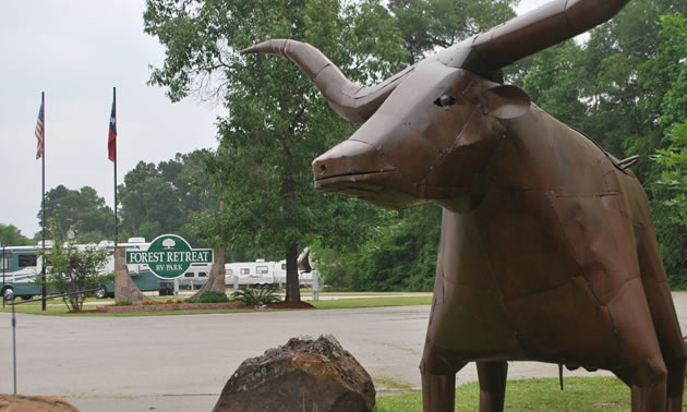 Picture of bull statue with Forest Retreat RV Park sign in background. 