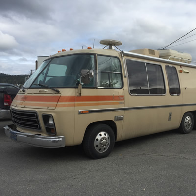 Picture of vintage GMC motorhome, silver and blue. 