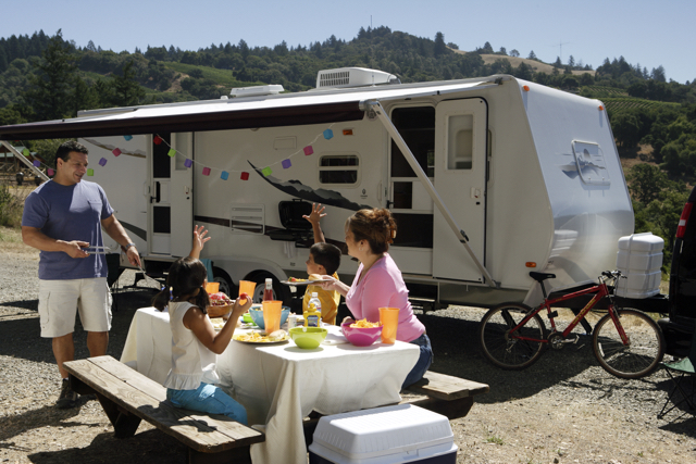 A family eating at a picnic table in front of their RV