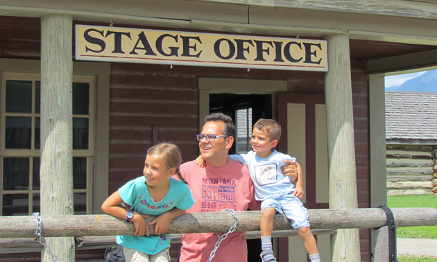 A man with two children stand outside a building bearing the sign 