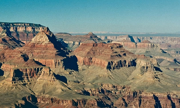 The Grand Canyon is shown on a sunny, blue-sky day.