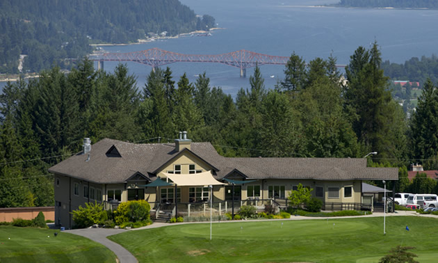 View of golf club house on hill, with lake in background.