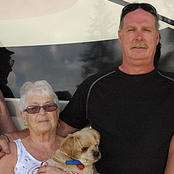 Two couples and one small dog stand beside their motorhome