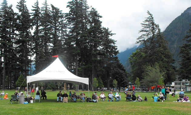 An audience sits beneath an outdoor tent in Hope's Memorial Park.