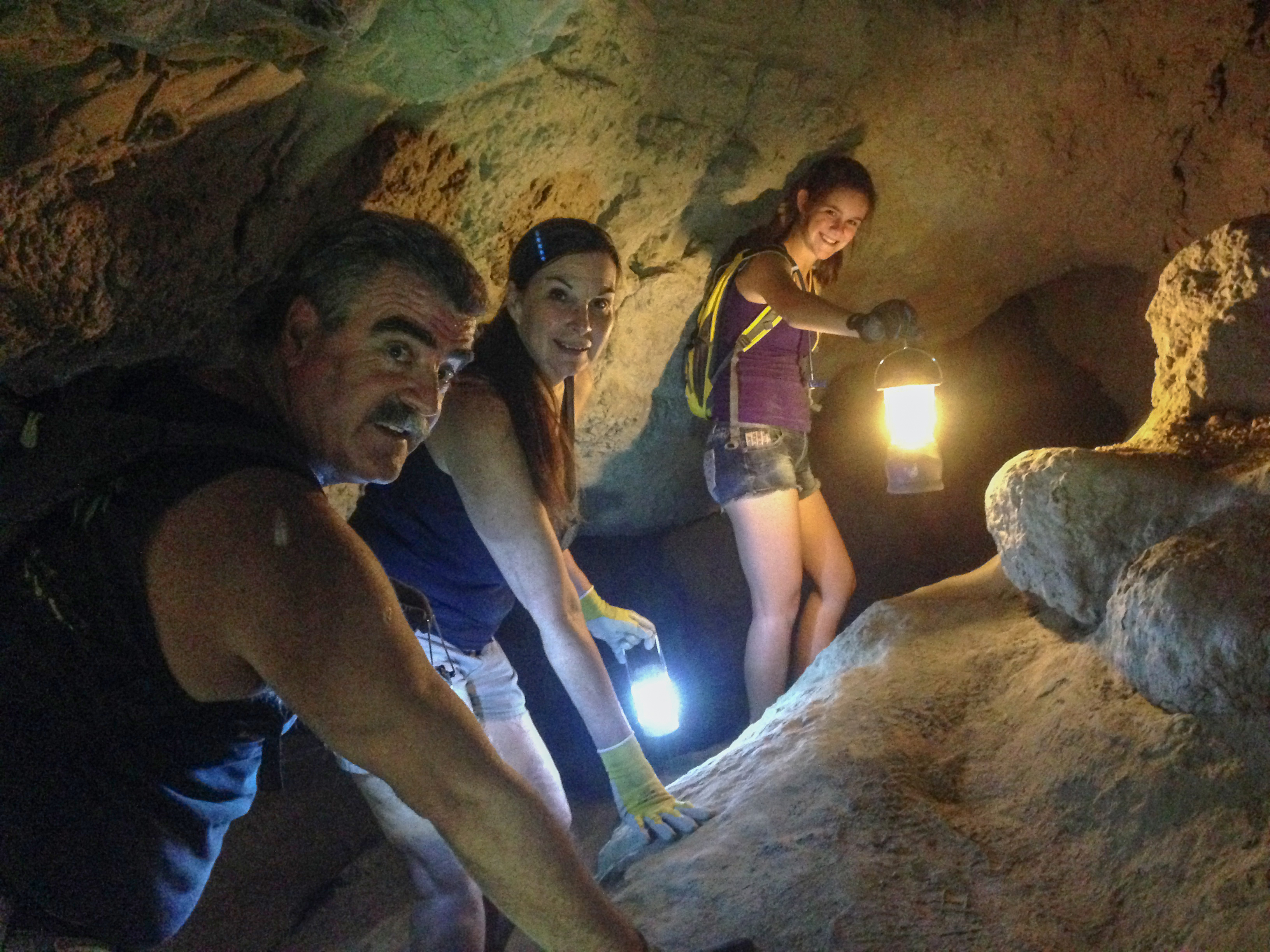 Haley Jones (rear) leads her grandparents, Don and Cher Kelley, into a dark mud cave using lanterns for light.