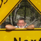 Man poses next to a road sign of a camel, a kangaroo and a wombat in Australia