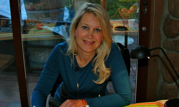 Smiling young blonde woman wearing a long-sleeved teal blue T-shirt