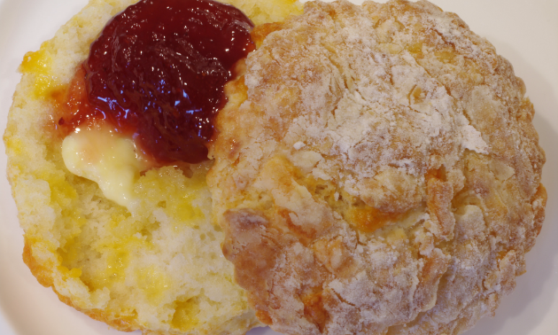 A buttermilk biscuit with strawberry jam and butter looks tasty.