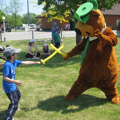 Person in Yogi Bear costume and child sparring with foam swords. 