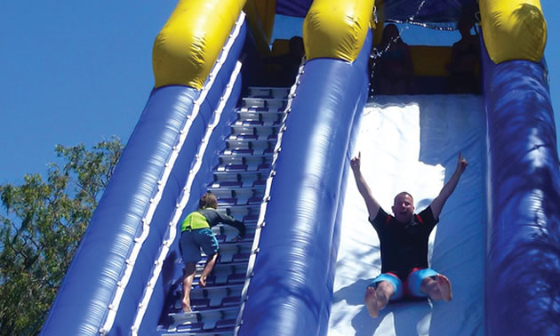 Man and child sliding down inflatable water slide. 