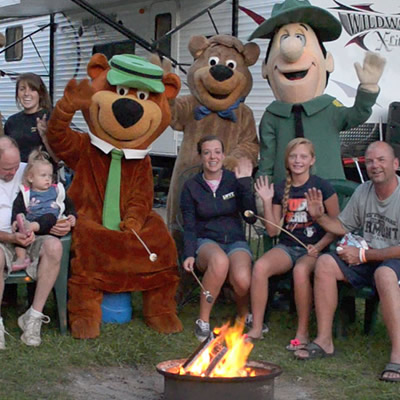 Jellystone guests and costumed characters around a campfire.  