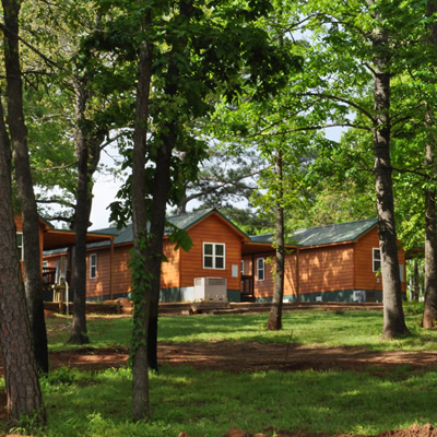 Picture of wooden cabins seen through a grove of trees. 