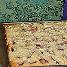 Hands hold a baking sheet containing a fruit crumble.