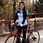 Kieren stands beside her red bicycle on a footbridge.