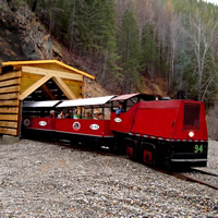 The Kimberley Underground Mining Railway little red train exits a log tunnel structure.