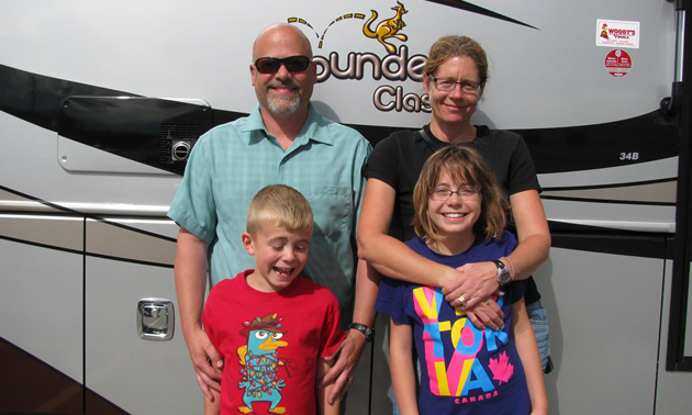 Couple with two young children and a large RV behind them