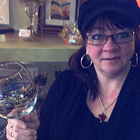 Woman in a shop holding a handpainted glass. 