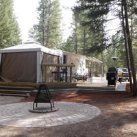 RV with an attached gazebo-style room and awning, wooden deck and adjacent fireplace