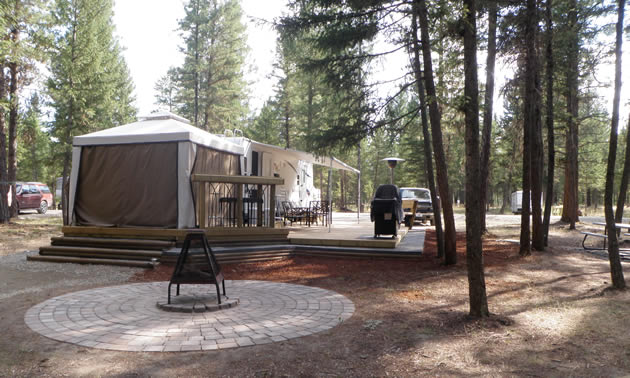 RV with an attached gazebo-style room and awning, wooden deck and adjacent fireplace