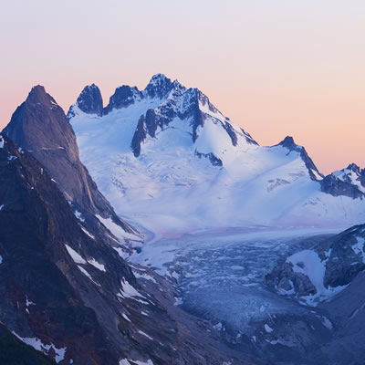 Mountain range with snow, pink sky background. 