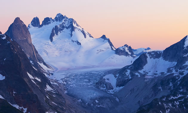 Mountain range with snow, pink sky background. 