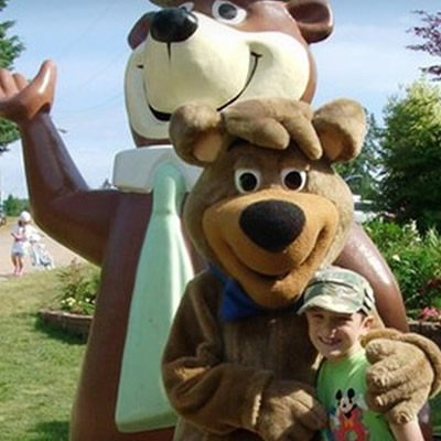 Child posing with a Yogi Bear mascot. 