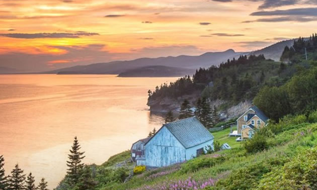 View of quaint lakeside cabin, with sunset. 