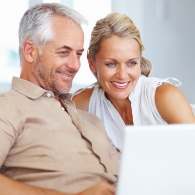 A couple is sitting and using a laptop. 