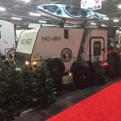 Picture of trailer surrounded by fake pine trees. 