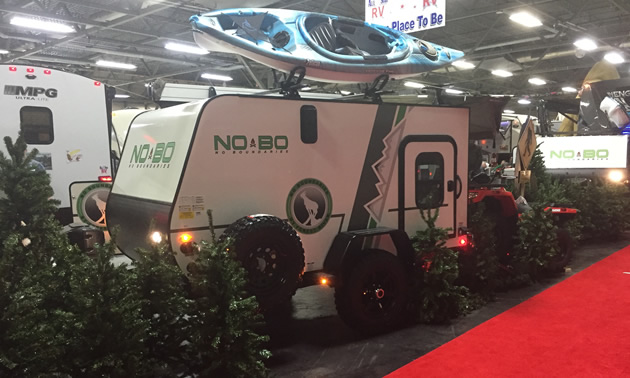 Picture of trailer surrounded by fake pine trees. 