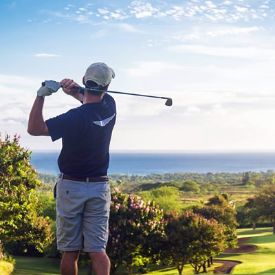 Man golfing with ocean vista in background. 
