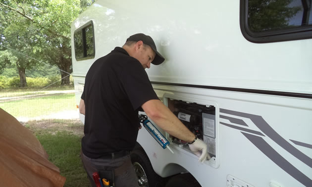 Reace adds a bit of sealant along the refrigerator drain pan at the customer’s request.