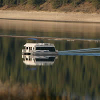 Houseboat on calm water that mirrors the shore and trees