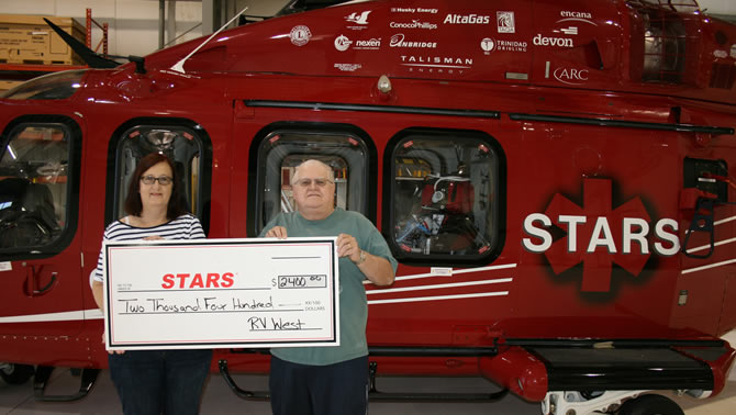 Duane and Lynda Pilson proudly present STARS with a cheque for $2,400 gathered at the 11th Annual RV West Rally held in Stettler.