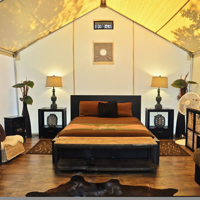 Inside of safari tent, with nice bed and furnishings. 